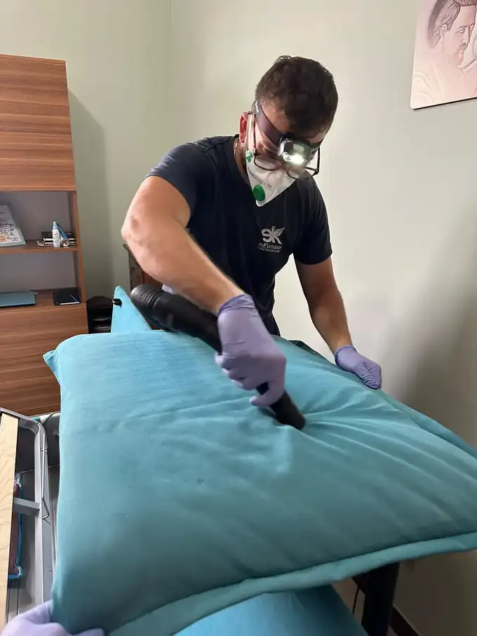 Tecnico Ekonore ispeziona e aspira un materasso con lampada frontale durante la disinfestazione delle cimici dei letti