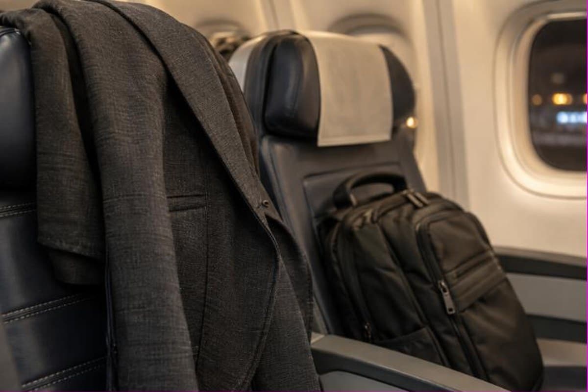 Giacca e zaino da cabina appoggiati sui sedili dell’aereo